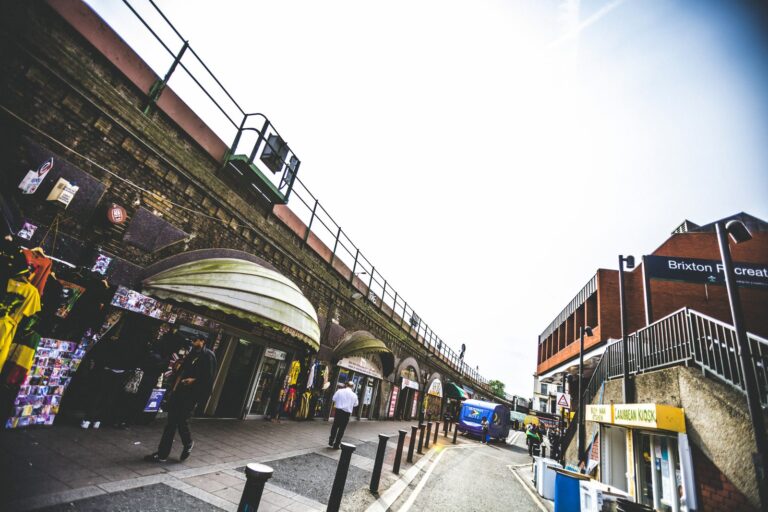 Independent shops and clothing stalls tucked under Brixton's railway arches, with the Brixton Recreation Centre visible to the right