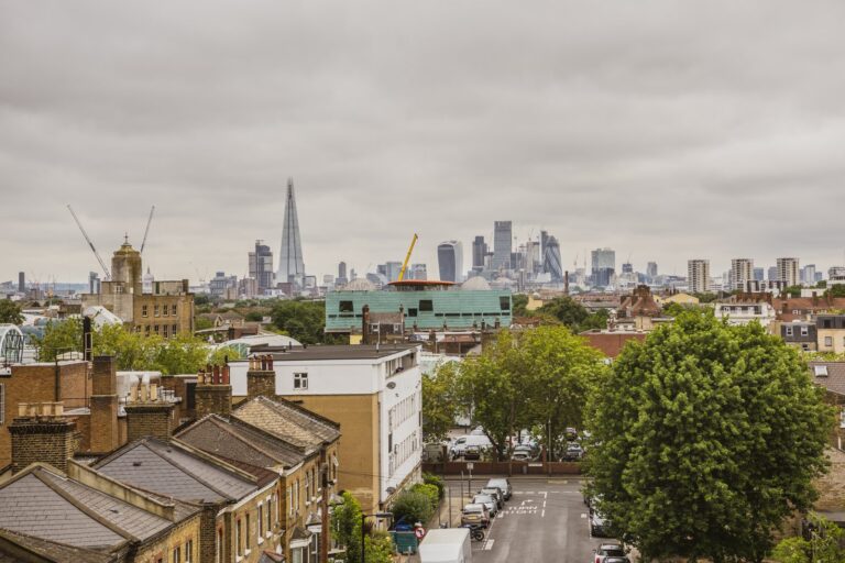 View across Peckham's Victorian terraces and tree-lined streets toward the City of London skyline, with the Shard and Cheesegrater visible on the horizon