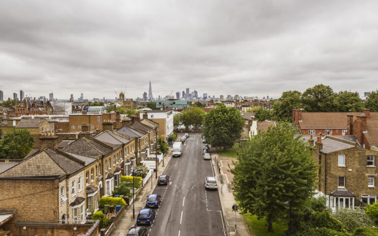 A quiet Peckham residential street of Victorian terraces leading toward the Shard and the City of London on the horizon